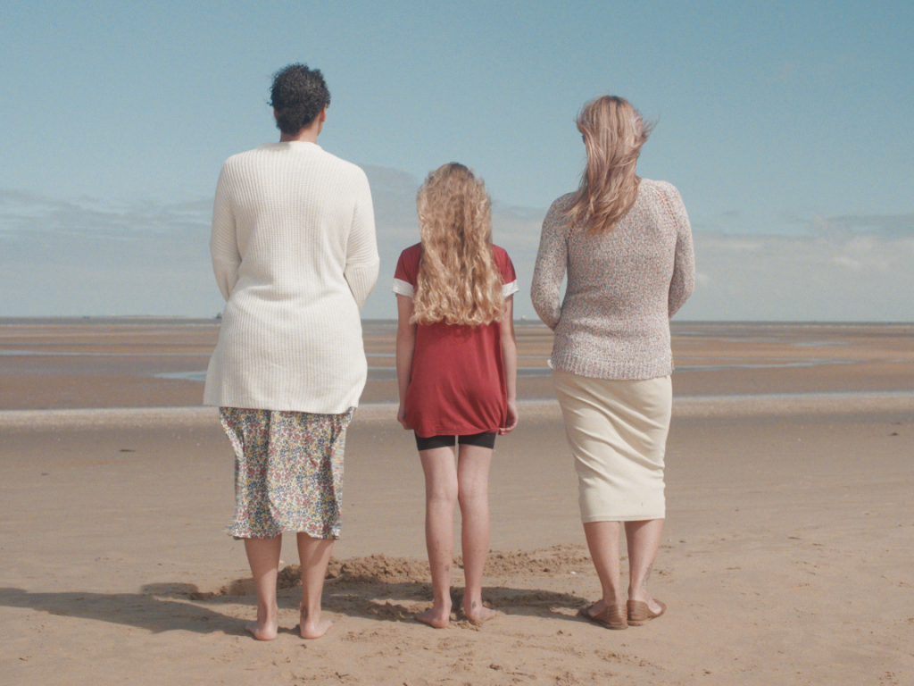 Two women and a child standing on a beach