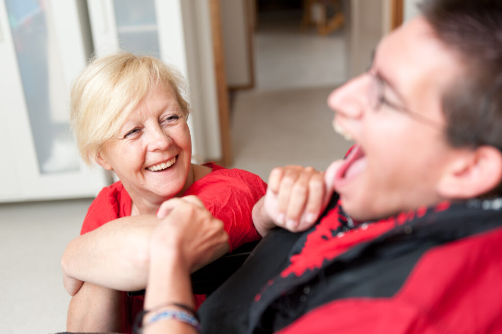 Short Break Carer and young man laughing in wheelchair